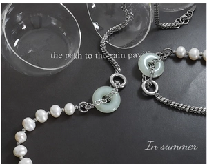 Détail de collier en perles avec anneaux de jade et chaîne en acier titane argenté
