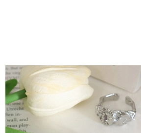Détail de la bague argentée à texture lave sur un fond blanc minimaliste