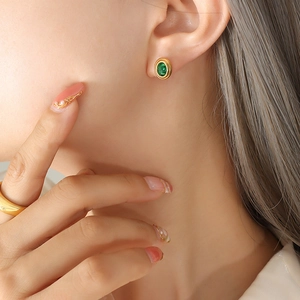Pendientes retro franceses de titanio dorado con circón verde usados por una modelo