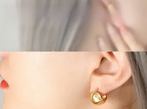 Close-up of chunky gold-plated C-shaped earrings with a high-polished mirror finish