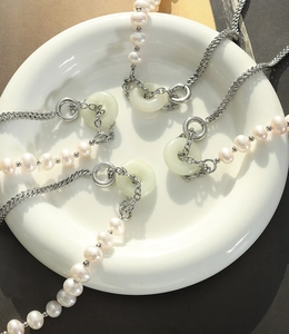 Détail d'un collier de perles d'eau douce avec pendentif en jade et chaîne en acier