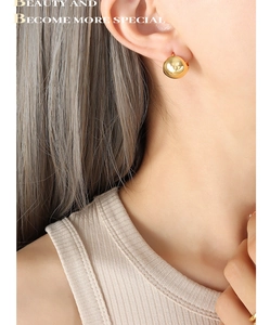 Close-up of minimalist golden spherical earrings with a polished mirror finish on model