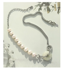 Détail du collier de perles et chaîne en acier avec un pendentif anneau en jade