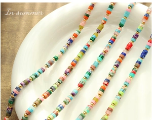 Close-up of bohemian natural stone cylinder beads with gold spacers on a ceramic plate