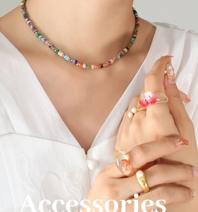 Detail of colorful stone beaded necklace and resin rings with embedded dried flowers
