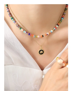 Detail of colorful beaded necklace, rose relief pendant, and floral resin ring on model