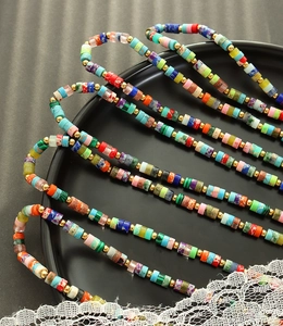 Detail of colorful heishi bead necklaces with golden spacers on a black ceramic tray
