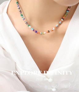 Close-up of bohemian colorful stone beaded necklace with golden spacers on a white shirt