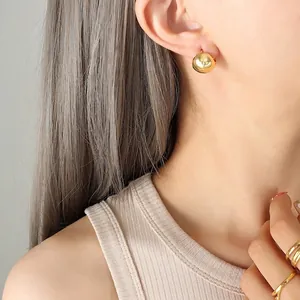 Minimalist gold spherical stud earrings with mirror finish shown on a model's ear