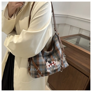 Detail of plaid tote bag featuring cartoon dog print and slim leather shoulder straps