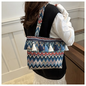 Dettaglio borsa tote tessuta boho con motivi geometrici colorati e nappe blu eleganti