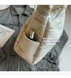 Detail of canvas bag side pocket with colorful embroidery showing storage space