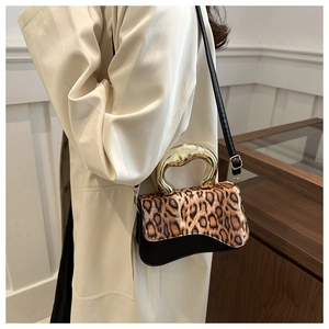 Close-up of leopard print handbag featuring a unique gold metal handle and leather strap