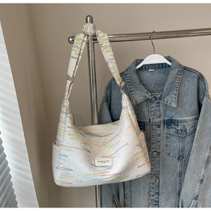 Detail of white hobo bag featuring colorful graffiti stripes and woven brand label