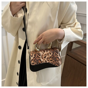 Detail of leopard print handbag with golden metal handles and black leather trim