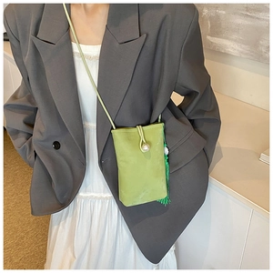 Close-up of light green crossbody phone bag with pearl buckle and long green tassel detail