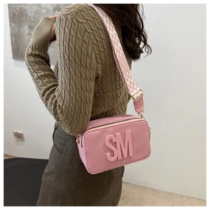 Sac bandoulière rose avec lettres en relief et large bandoulière tissée