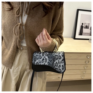 Detailed shot of leopard print handbag with a circular gold metal handle on a model