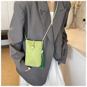 Detail of light green mini crossbody bag with pearl clasp and silk tassel on model