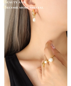 Detailansicht der Barockperlen-Ohrringe und eines goldenen Perlenrings am weiblichen Modell