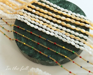 Detail of vintage shell bead necklace and gold chain with colorful enamel dot accents