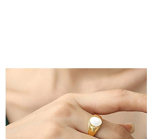 Macro shot of minimalist gold ring featuring a polished oval white shell inlay on finger