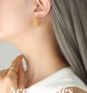 Detail of C-shaped hollow mesh earrings and vintage gold watch ring with clear zircon