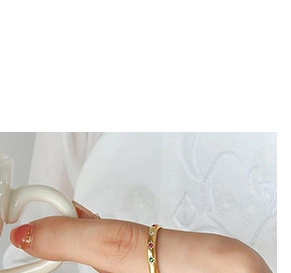 Close-up of a gold ring with red, green and white stones on a model's hand