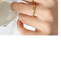 Close-up of gold titanium steel rings with red, green, and white zircon stone inlay