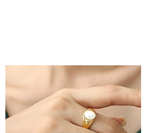 Macro view of a gold-plated signet ring with an elegant oval white shell inlay on finger