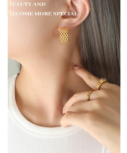 Detail of 18K gold plated mesh C-shaped hoop earrings and gemstone rings on model