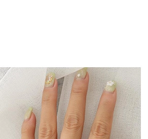 Detail of light green press-on nails with 3D white flowers and small pearl accents