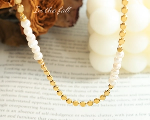 Gros plan d'un collier de perles d'eau douce et perles dorées sur un livre vintage