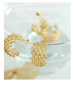 Detailed macro view of golden honeycomb C-shaped hoop earrings with intricate beadwork