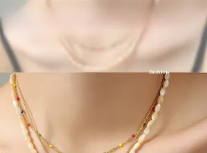 Close-up of layered gold titanium necklace with colorful beads and white shell pendants