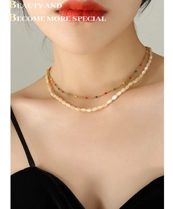 Close-up of double-layer vintage gold chain necklace with colorful beads and white shells