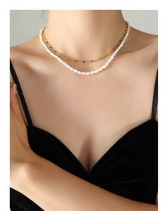 Close-up of a layered gold chain necklace with colorful beads and white shell pearls