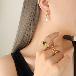 Goldene C-förmige Ohrringe mit Barockperlen und strukturierte Ringe getragen von Model