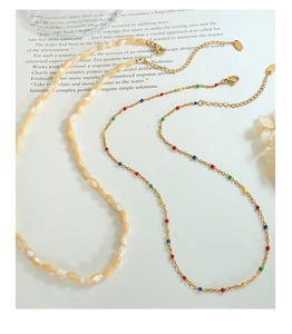 Close-up of vintage French shell necklaces with colorful enamel dots and orange beads