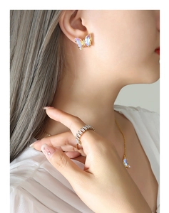 Close-up of butterfly necklace, earrings and baguette-cut ring jewelry set on model