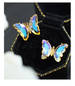 Close-up of butterfly earrings with AB crystal wings and gold frame on velvet box
