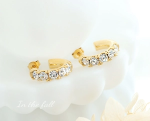 Vue détaillée de boucles d'oreilles en titane doré en forme de C serties de zircons blancs
