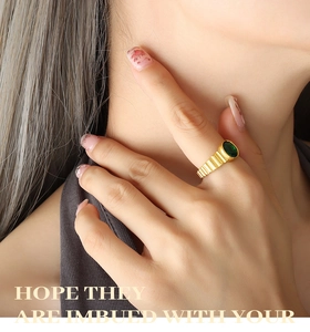 Gros plan d'une bague plaquée or 18K avec zircon vert et texture horizontale unique