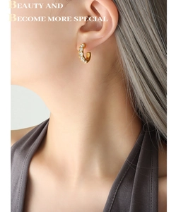 Gros plan de boucles d'oreilles en C plaquées or 18 carats avec zircons blancs incrustés