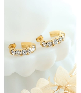Détail des boucles d'oreilles dorées en C avec cinq zircons étincelants incrustés