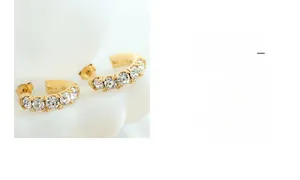 Détail macro de boucles d'oreilles dorées en C avec zircons blancs et fermoir papillon