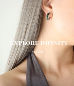 Détail de boucles d'oreilles en acier titane en C avec zircons blancs et vert émeraude