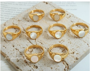 Detail of vintage gold-plated signet rings with oval white shell inlays on stone tray