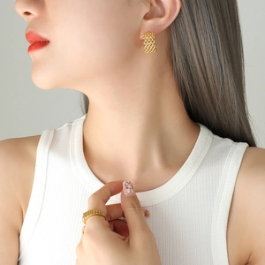 Golden dreamcatcher C-shaped earrings and wide textured ring set on female model