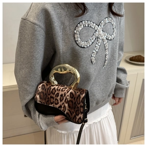 Detail of leopard print crossbody bag with vintage curved gold metal handle